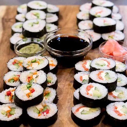 Sushi, soy sauce and chopsticks on wooden serving platter.