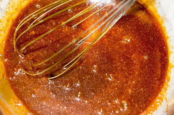 Wing sauce in a bowl being stirred by a spatula.