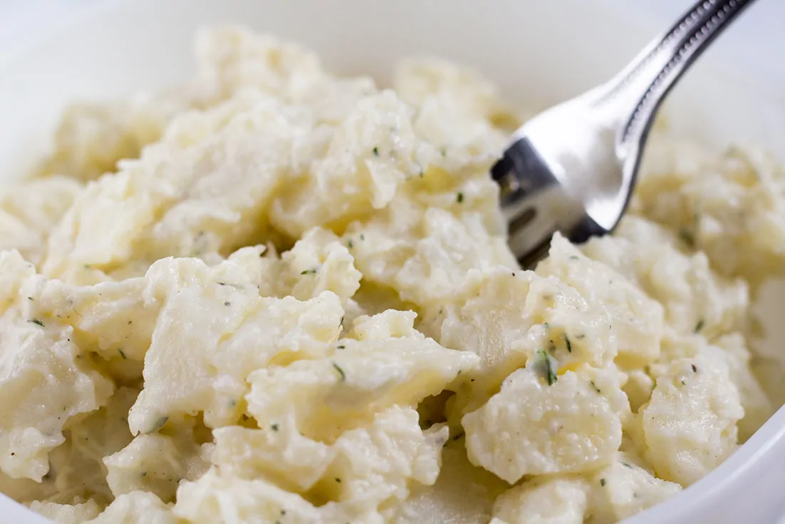 Vegan Potato Salad in white bowl with fork.