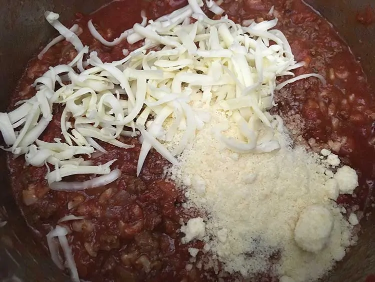 Sauce mixture topped with fontina and parmesan cheeses.