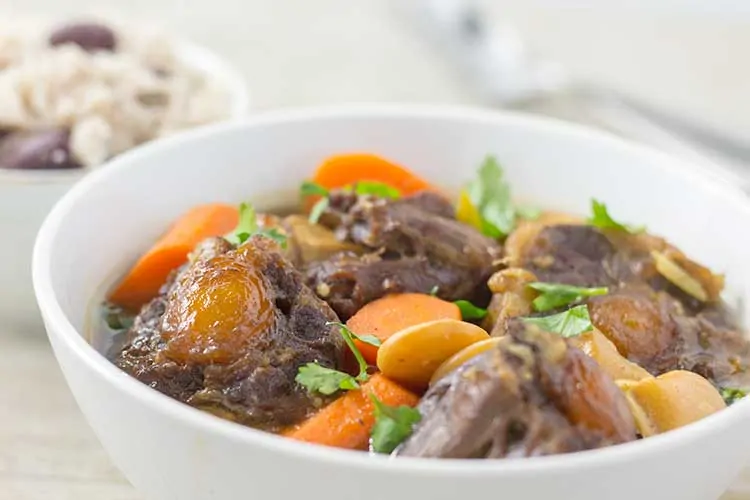 Pressure Cooker Oxtail Stew - Close-up in white bowl with coconut rice and peas | The Foodie Eats