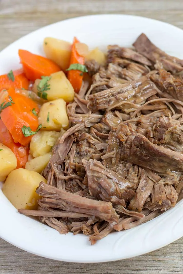 Pressure Cooker Pot Roast in white bowl with veggies.