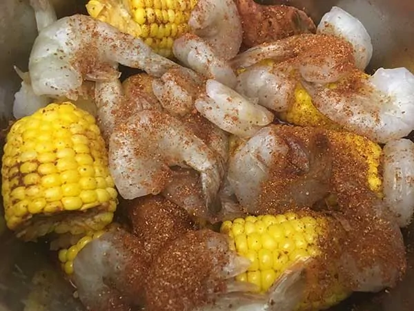 Uncooked shrimp on top of corn covered with spice blend.