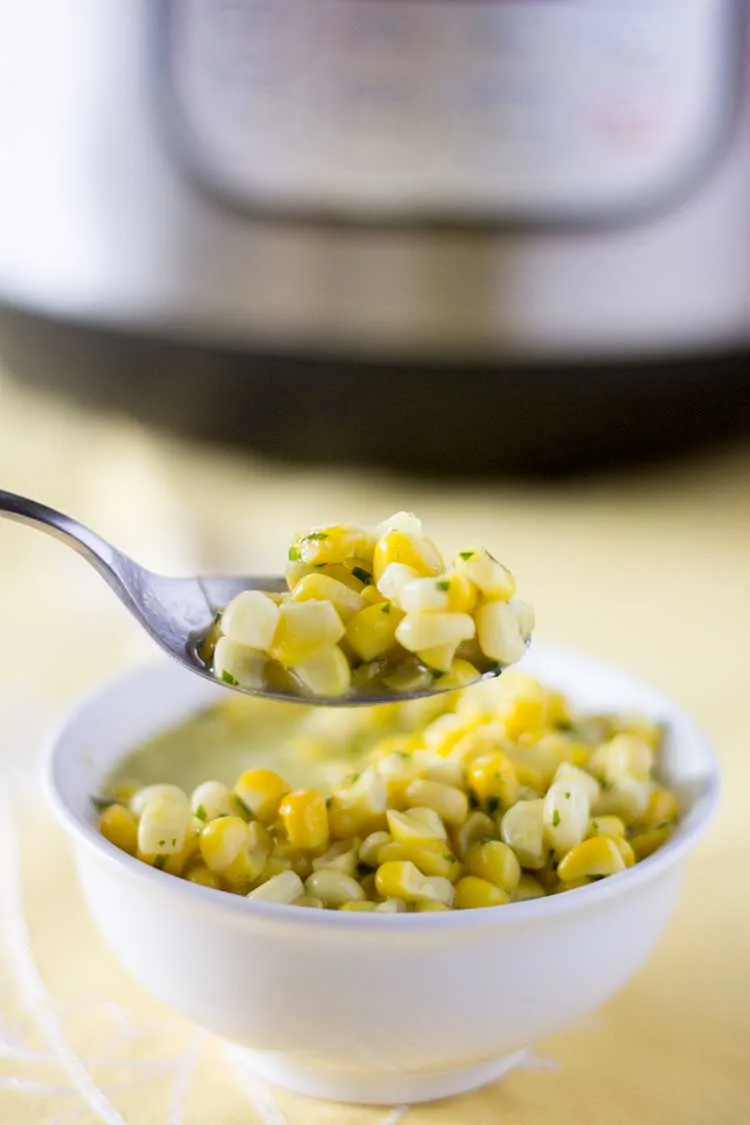 Instant Pot Creamed Corn in small white bowl with spoon.