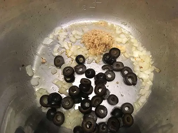 Diced onions sautéing with garlic and olives.