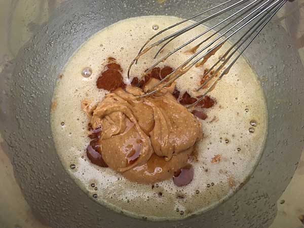 peanut butter being whisked into butter, sugar and egg mixture