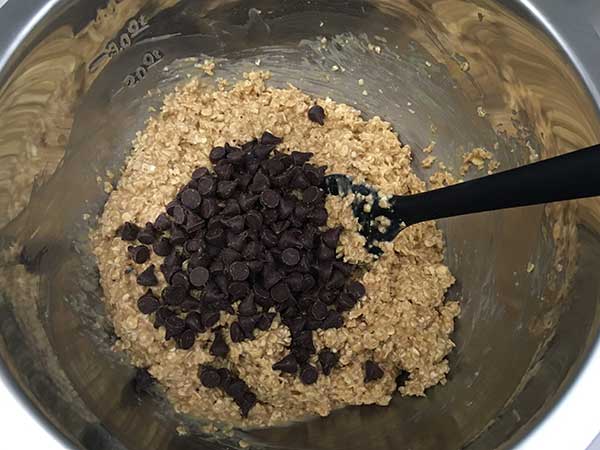 chocolate chips in bowl with oatmeal mixture and black spatula