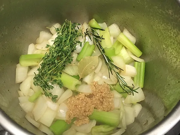Chopped onions and celery in Instant Pot with other aromatics.