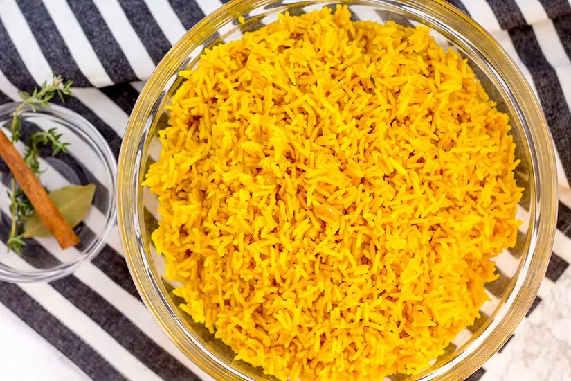 Yellow rice seen from above in a clear glass bowl.