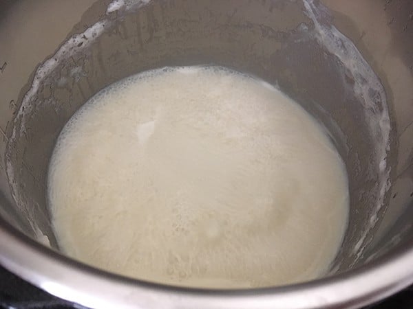 Milk and sugar mixture foaming as it simmers in the Instant Pot.