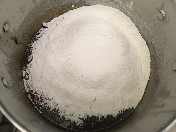 sifted flour on top of dried fruits in pot