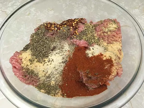 ground pork covered in spices in glass bowl