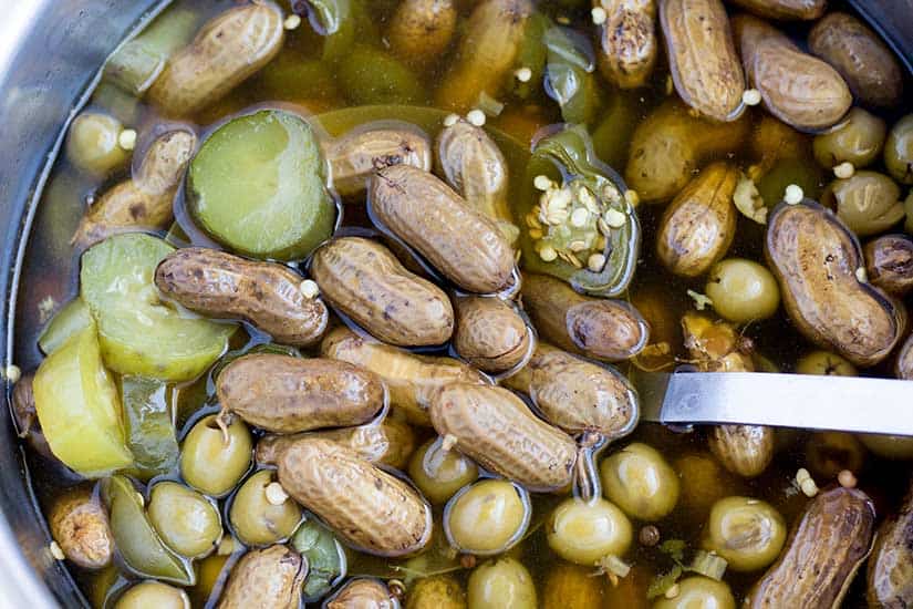 boiled peanuts in Instant Pot with sliced pickles, jalapenos, and olives.