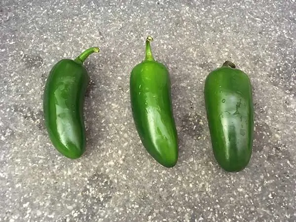 3 Jalapenos in cutting board.