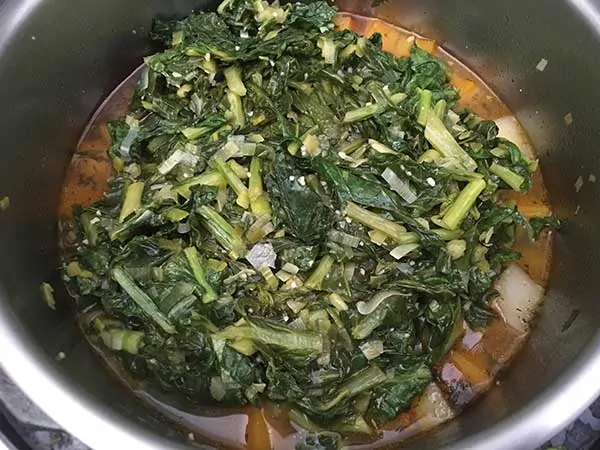 sautéed turnip greens on top of butternut squash, turnip roots, and Italian sausage in chicken broth