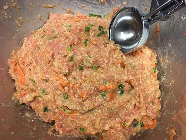 uncooked meatball mixture in mixing bowl with ice cream scoop