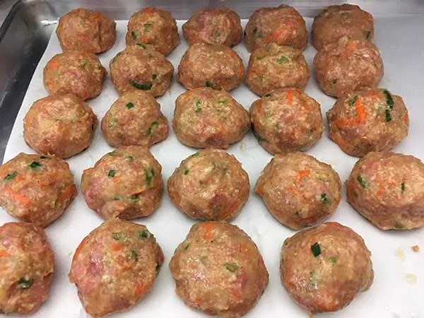 uncooked meatballs on parchment paper