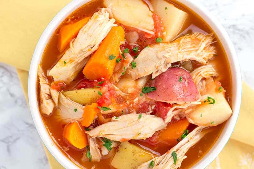 chicken stew in white bowl with yellow napkin