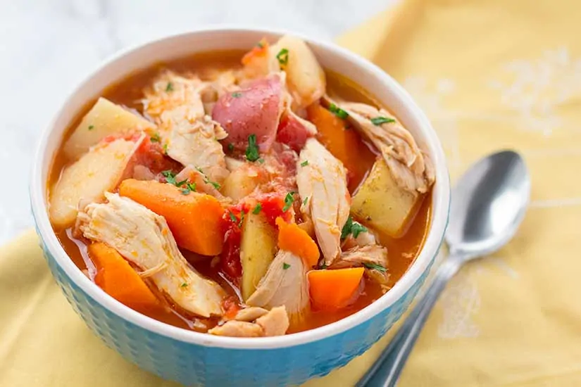 chicken stew in blue bowl with yellow napkin