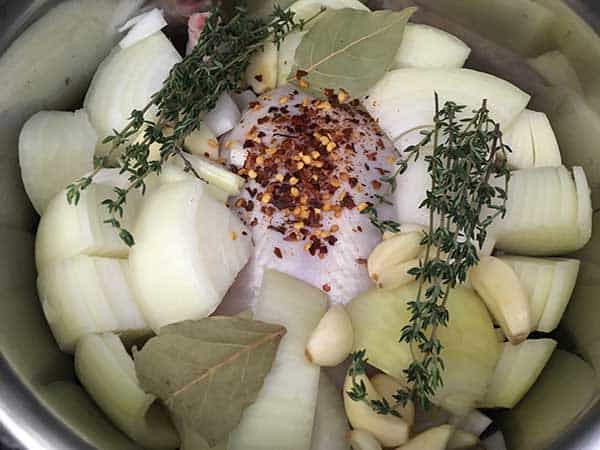 raw whole chicken in Instant Pot topped with aromatics