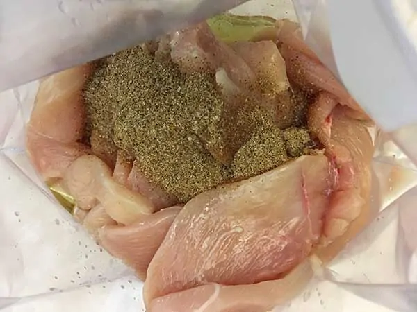 thinly sliced chicken topped with oil and spices in Ziplock back
