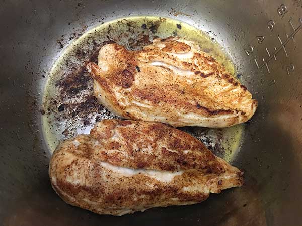 Two chicken breasts browning in Instant Pot.