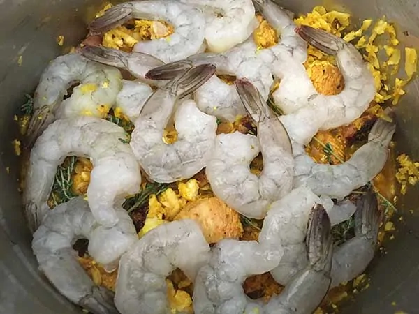 grated cauliflower and sausage seasoned with salt and turmeric, topped with raw shrimp