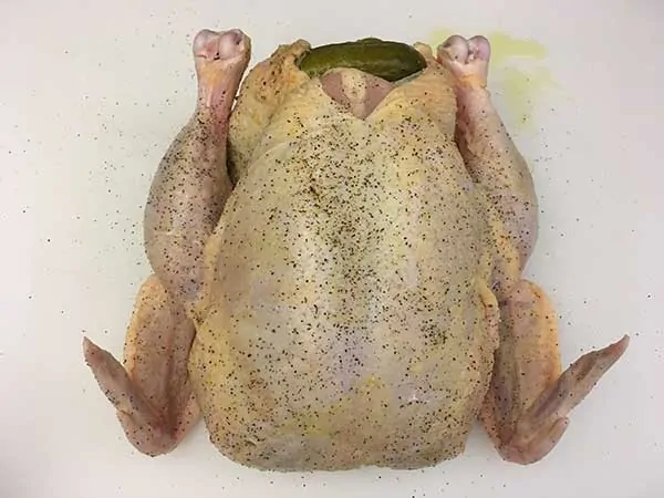 uncooked chicken stuffed with pickles on white cutting board