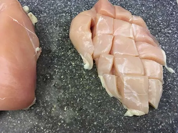 chicken breast cut into chunks on cutting board.