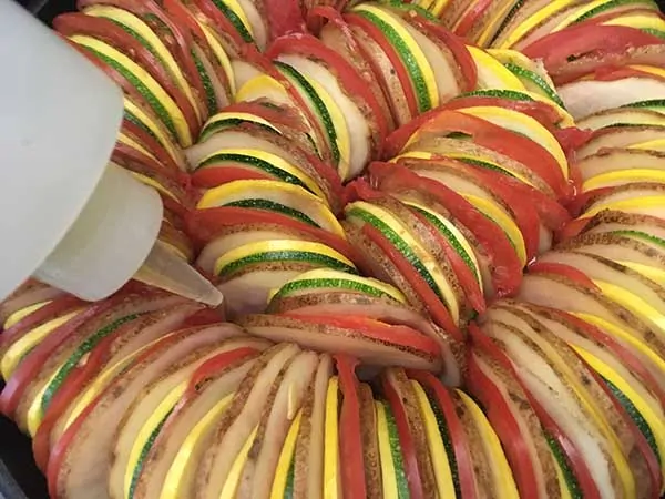 thinly sliced potatoes, tomatoes, zucchini, and squash in ratatouille pattern with plastic bottle