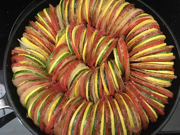 thinly sliced potatoes, tomatoes, zucchini, and squash in ratatouille pattern topped with sea salt