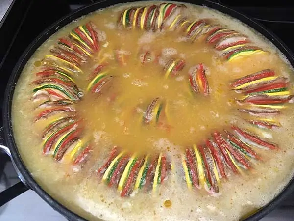 thinly sliced potatoes, tomatoes, zucchini, and squash in ratatouille pattern topped with raw eggs