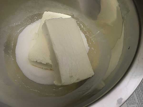 blocks of cream cheese in mixing bowl on to of sugar.