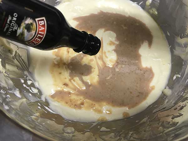 pouring Bailey's into blended cheesecake batter.