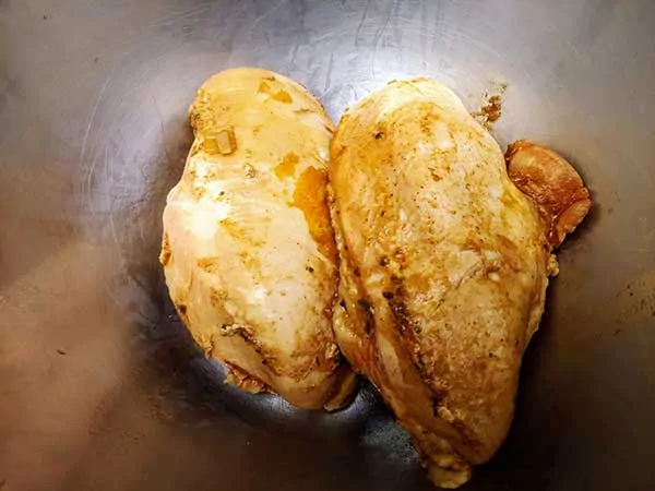 Chicken breasts in large bowl.
