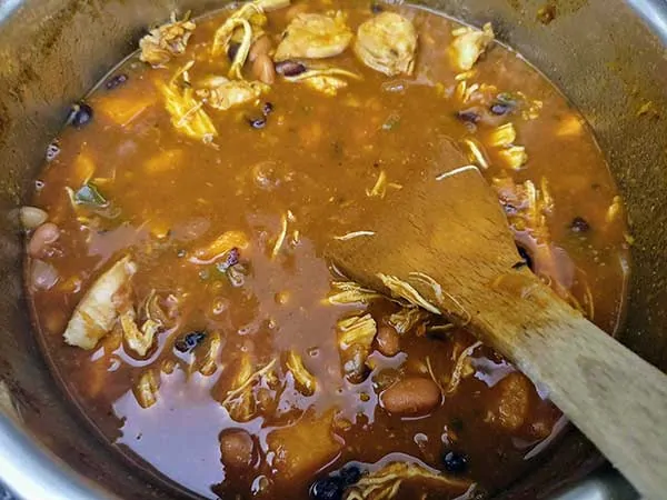 Sweet potato chicken chili in pot with wooden spoon.