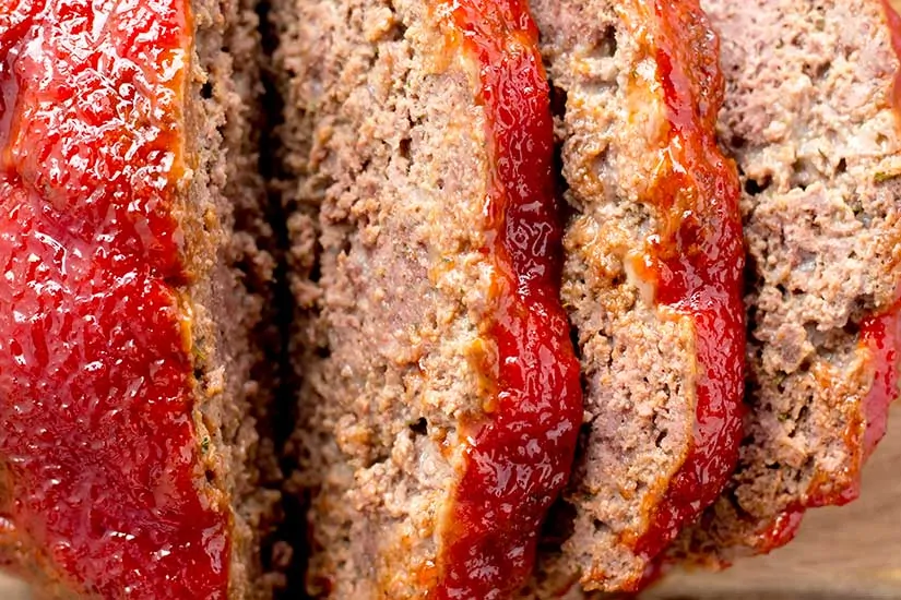 sliced meatloaf on wooden cutting board