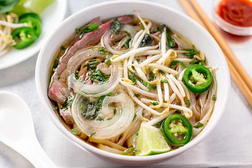 Beef pho in white bowl.