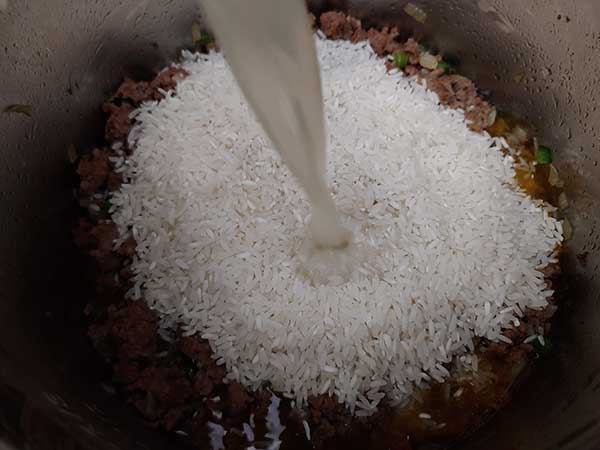 Pouring chicken stock over rice.