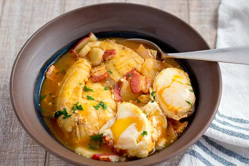Fish stew in brown bowl.