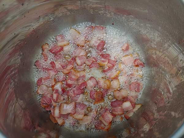 Bacon pieces frying in Instant Pot.