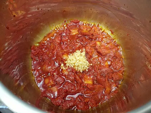 Minced garlic on top of tomato paste and bacon.