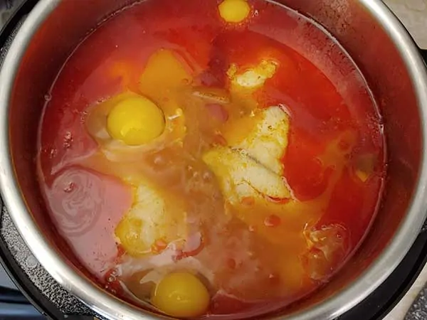 Raw eggs on top of fish stew.