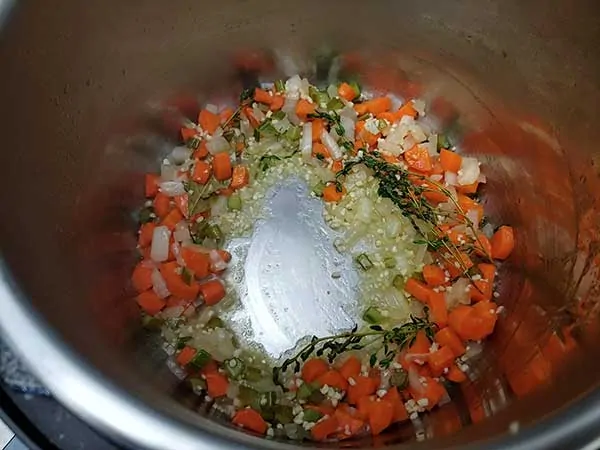 Mirepoix with garlic, bay leaf, and thyme in pot.