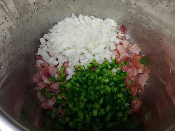 Cooked bacon topped with onions and green bell peppers.