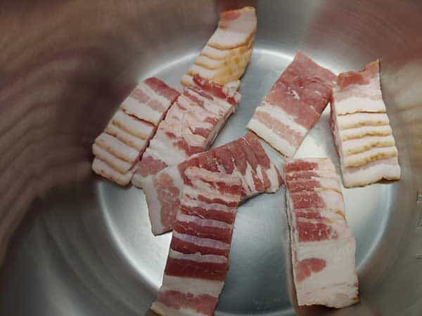 Sliced raw bacon cut into 1-inch pieces.