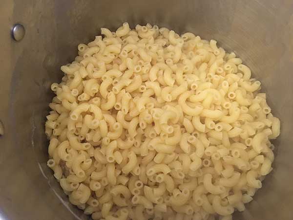 Cooked elbow pasta in pot.