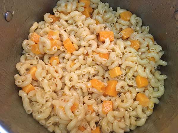 Cubed cheese melting in elbow pasta.