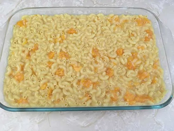Uncooked mac and cheese mixture in Pyrex baking dish.