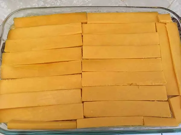 Sliced cheddar cheese layer in Pyrex dish.